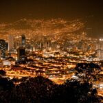 Vista panorámica de Medellín de noche, con la ciudad iluminada por las luces que resaltan los edificios y las calles.